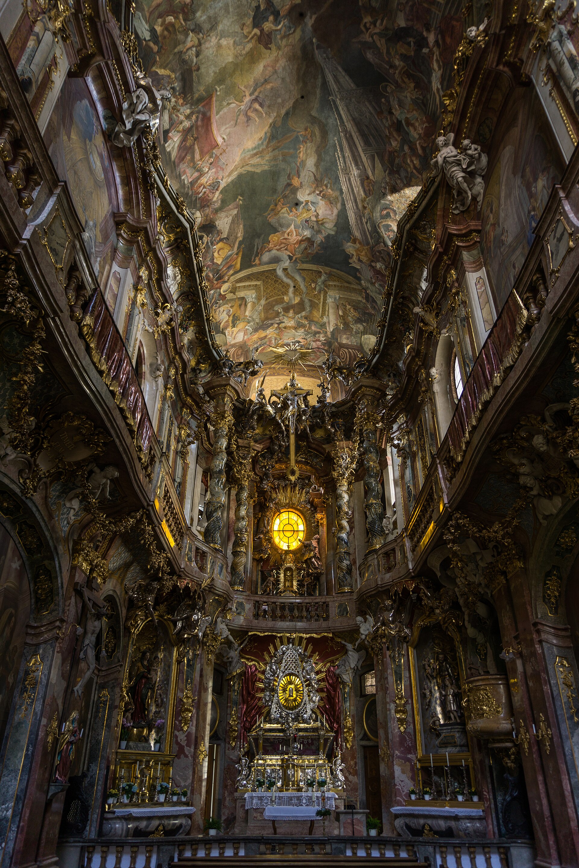 The interior of the Asam Church in Munich: a narrow, richly gilded Baroque nave with a frescoed vault.