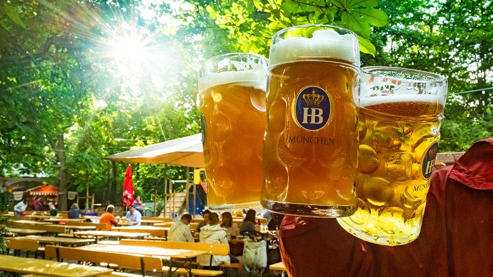 A Munich beer garden with long wooden tables under chestnut trees.